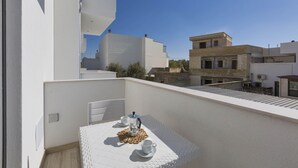 Un balcone con un tavolo apparecchiato per due persone, una macchina del caffè e una tazza.