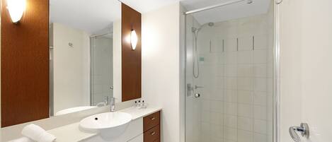 A modern bathroom with a double sink vanity, a large mirror, and a glass-enclosed shower area.