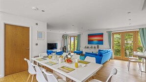 Ein modernes Wohnzimmer mit Essbereich, großen Fenstern und Blick ins Grüne.