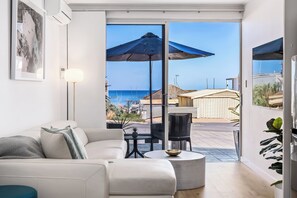 A modern living room with a white sofa, a round coffee table, and a view of the sea through large glass doors. - Steps to the sand | Belle Vista 2 Apartment Seacliff (Seacliff)