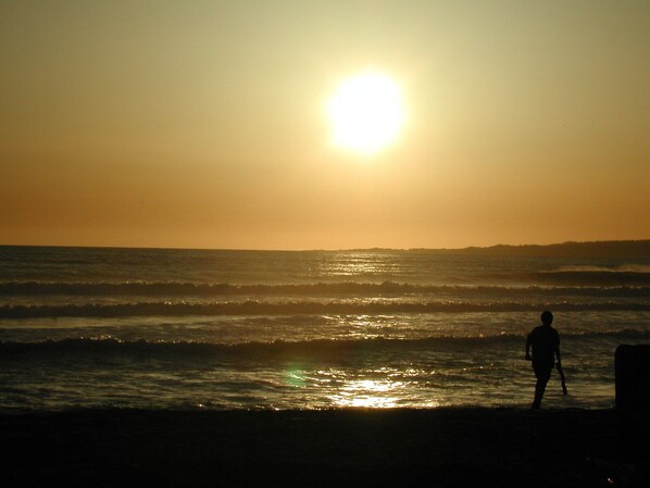 La silhouette d’une personne marchant sur une plage au coucher du soleil.