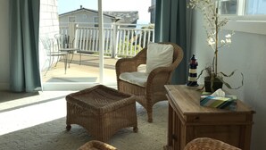 A balcony with wicker furniture, a potted orchid, and a lighthouse ornament. - Big and Bright,  Steps to Sand, Ocean Views, and Sleeps 8+ (La Selva Beach)