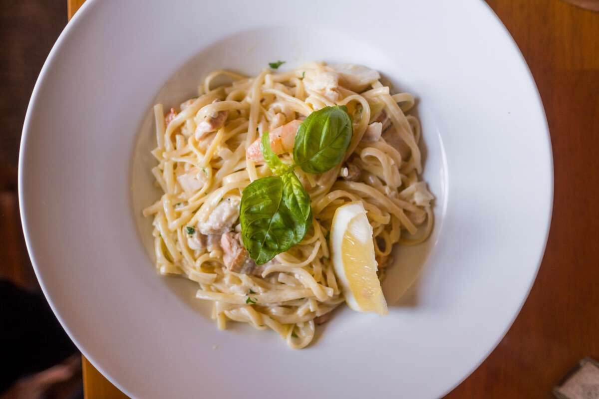 A bowl of pasta with lemon and basil garnish.