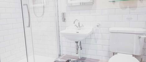 Un baño moderno con cabina de ducha de vidrio, un lavabo blanco y un inodoro.