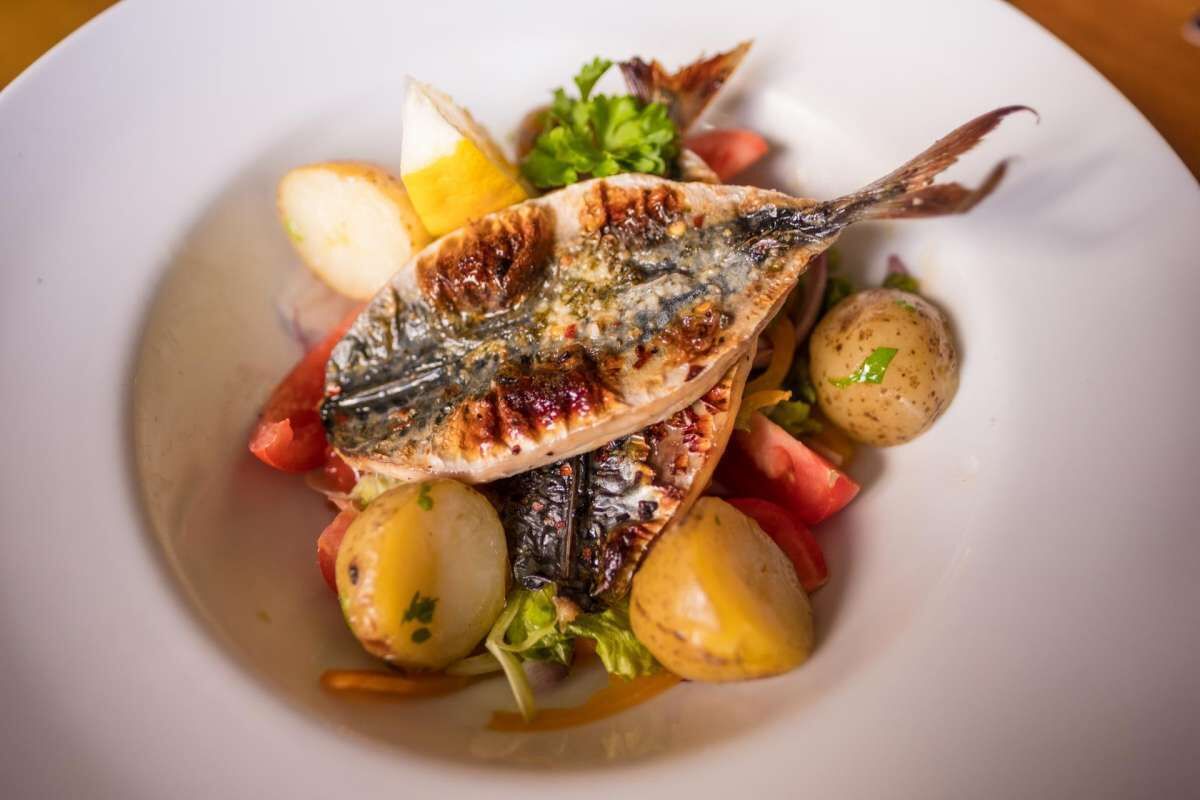 A plate with grilled fish, potatoes, and vegetables.