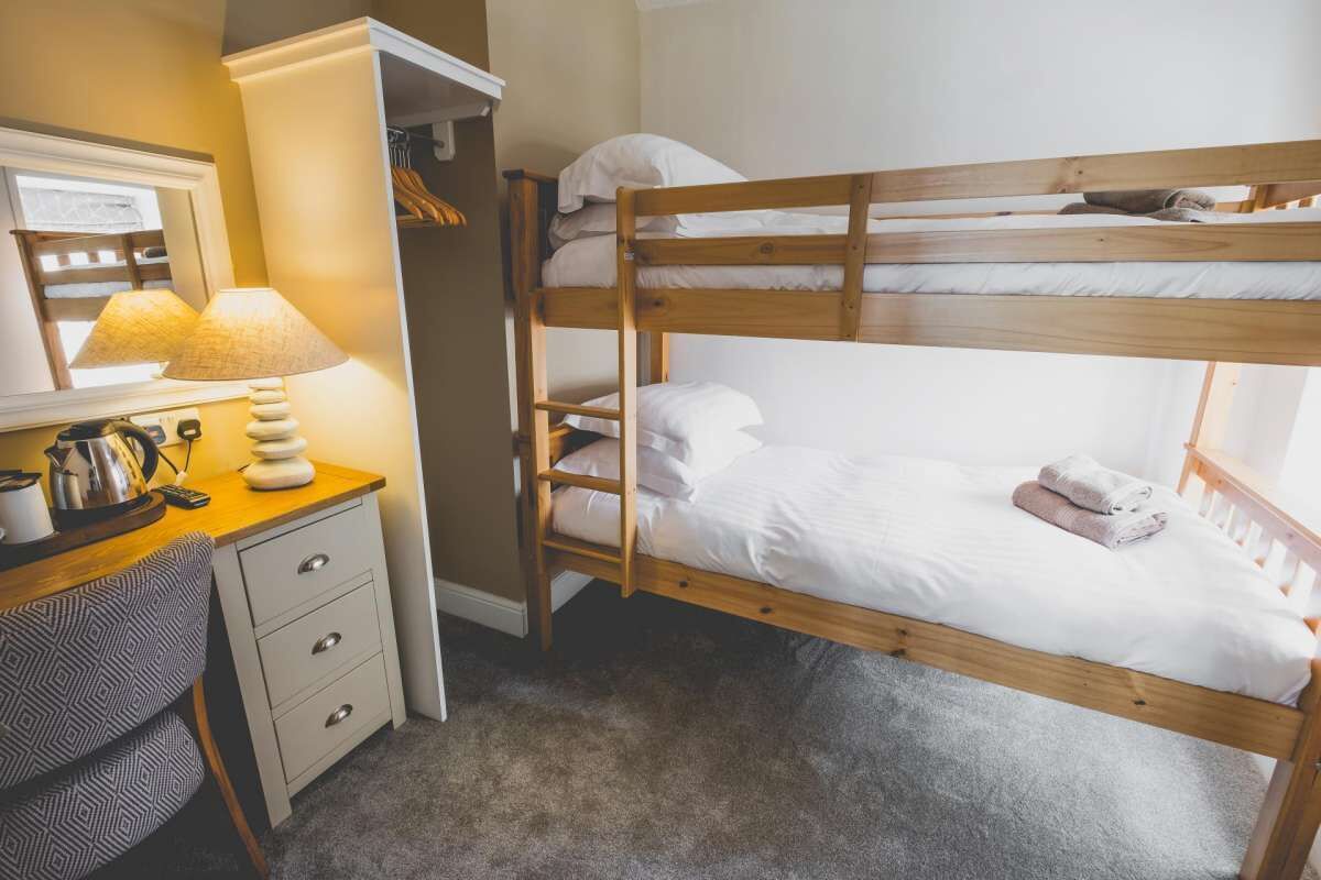 Un lit superposé avec un bureau et une chaise, une lampe et un miroir.