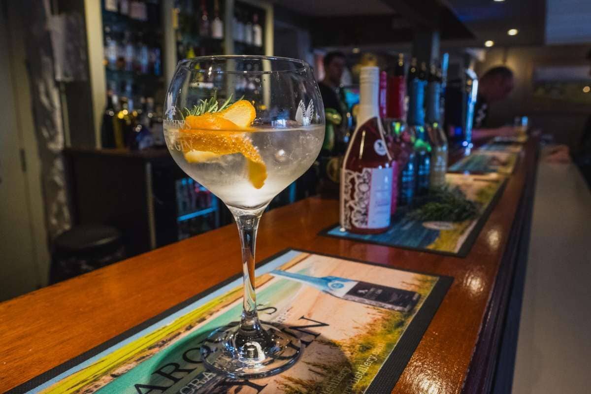A bar setting with a cocktail glass on a bar mat, bottles in the background, and a bar counter.