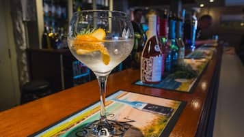 A bar setting with a cocktail glass on a bar mat, bottles in the background, and a bar counter.
