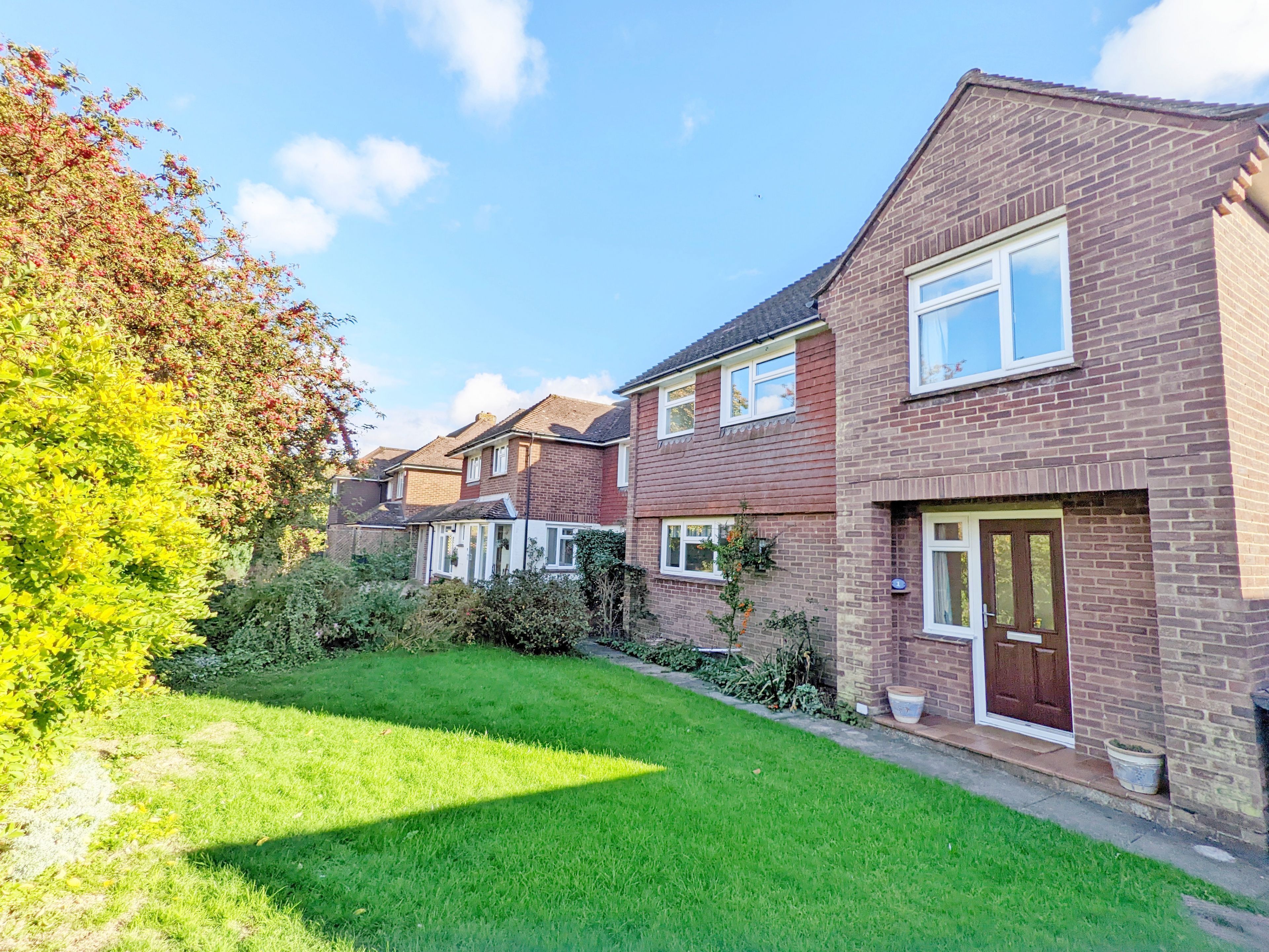 A row of brick houses with a well-maintained lawn and a clear sky.