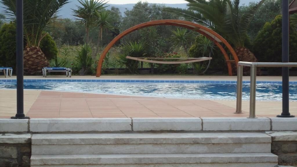 A swimming pool with a stone border, a wooden swing, and steps leading down to the water.