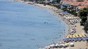 Une plage côtière avec de nombreux parasols et beaucoup de monde.