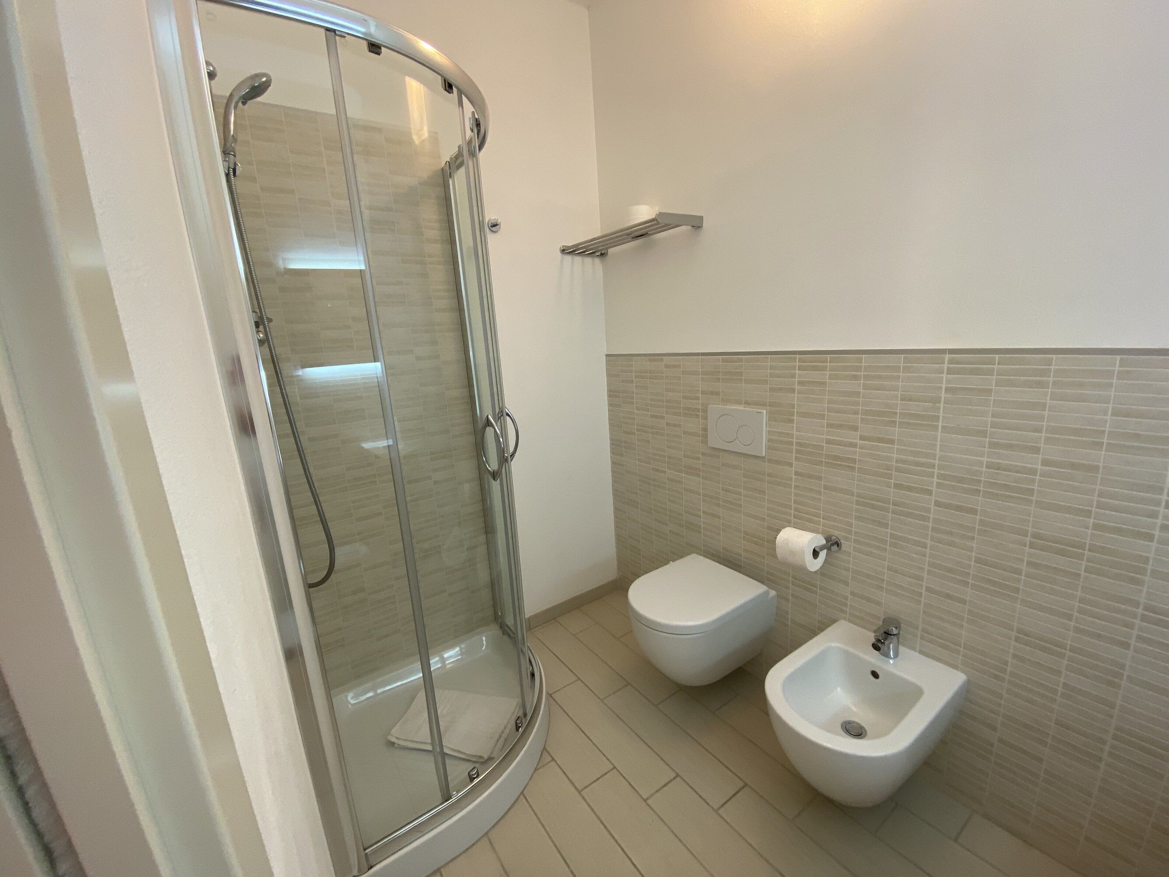 Une salle de bain moderne avec une douche à parois de verre, un bidet et des toilettes.