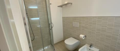 Une salle de bain moderne avec une douche à parois de verre, un bidet et des toilettes.