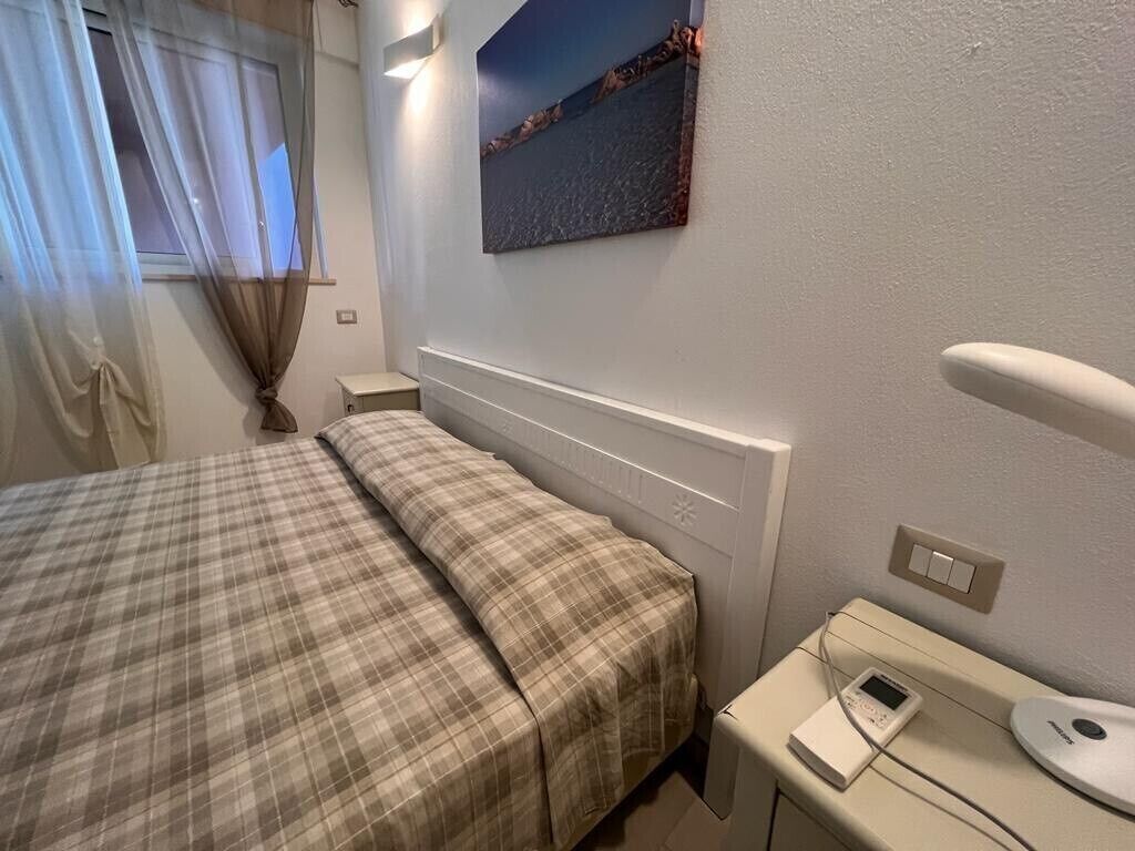 A bedroom with a bed, bedside table, and a wall-mounted artwork.
