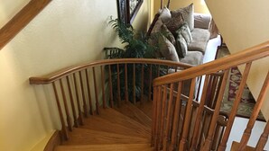 A wooden staircase with a handrail leading to a living room area with a sofa and a potted plant. - CASA COLONIAL PLAYAS  CHAPULTEPEC DOS CUADRAS DE LA PLAYA GRANDE PARKING ADENTRO (Colonia Playas de Chapultepec Ensenada)