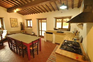 A kitchen with a wooden table and chairs, a stove, and a window. - House in the woods, entire house free on 4 sides in the Tuscan hills (Rufina)