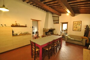 A spacious kitchen with a long dining table, wooden chairs, and a striped sofa. - House in the woods, entire house free on 4 sides in the Tuscan hills (Rufina)