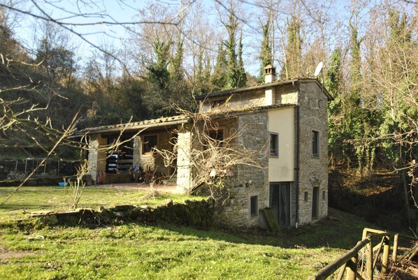 A stone house with a sloped roof, a small porch, and a satellite dish. - House in the woods, entire house free on 4 sides in the Tuscan hills (Rufina)