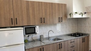A kitchen with wooden cabinets, a white refrigerator, a microwave, a sink, and a stove.