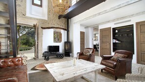 Ein großzügiger Wohnbereich mit Kamin, Ledersofas und einer rustikalen Steinwand.
