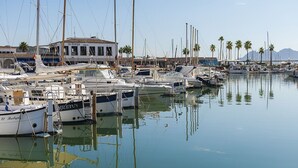 Ein Yachthafen mit mehreren vertäuten Booten, ein Gebäude mit Ziegeldach und im Hintergrund Palmen.