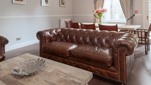 A spacious living room with a leather sofa, wooden coffee table, and a chandelier. - Apartment in Prestigious location Central Edinburgh  (Edinburgh)