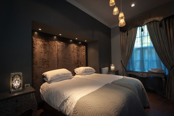 A modern bedroom with a large bed, a stone accent wall, and a window with curtains.