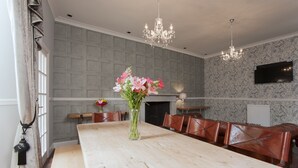 A dining area with a long wooden table, leather chairs, a vase of flowers, and a chandelier. - Apartment in Prestigious location Central Edinburgh  (Edinburgh)