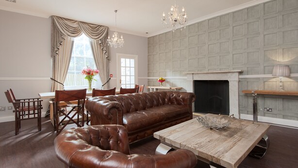 A living room with a brown leather sofa, wooden coffee table, and chandelier. - Apartment in Prestigious location Central Edinburgh  (Edinburgh)