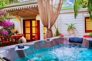 Un jacuzzi con toldo color beige, rodeado de mobiliario exterior y plantas en macetas.