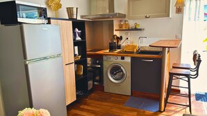 Una cocina compacta con refrigerador, lavadora y encimera de madera.