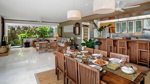 Un comedor amplio con una larga mesa de madera dispuesta para una comida, rodeado de sillas de madera.