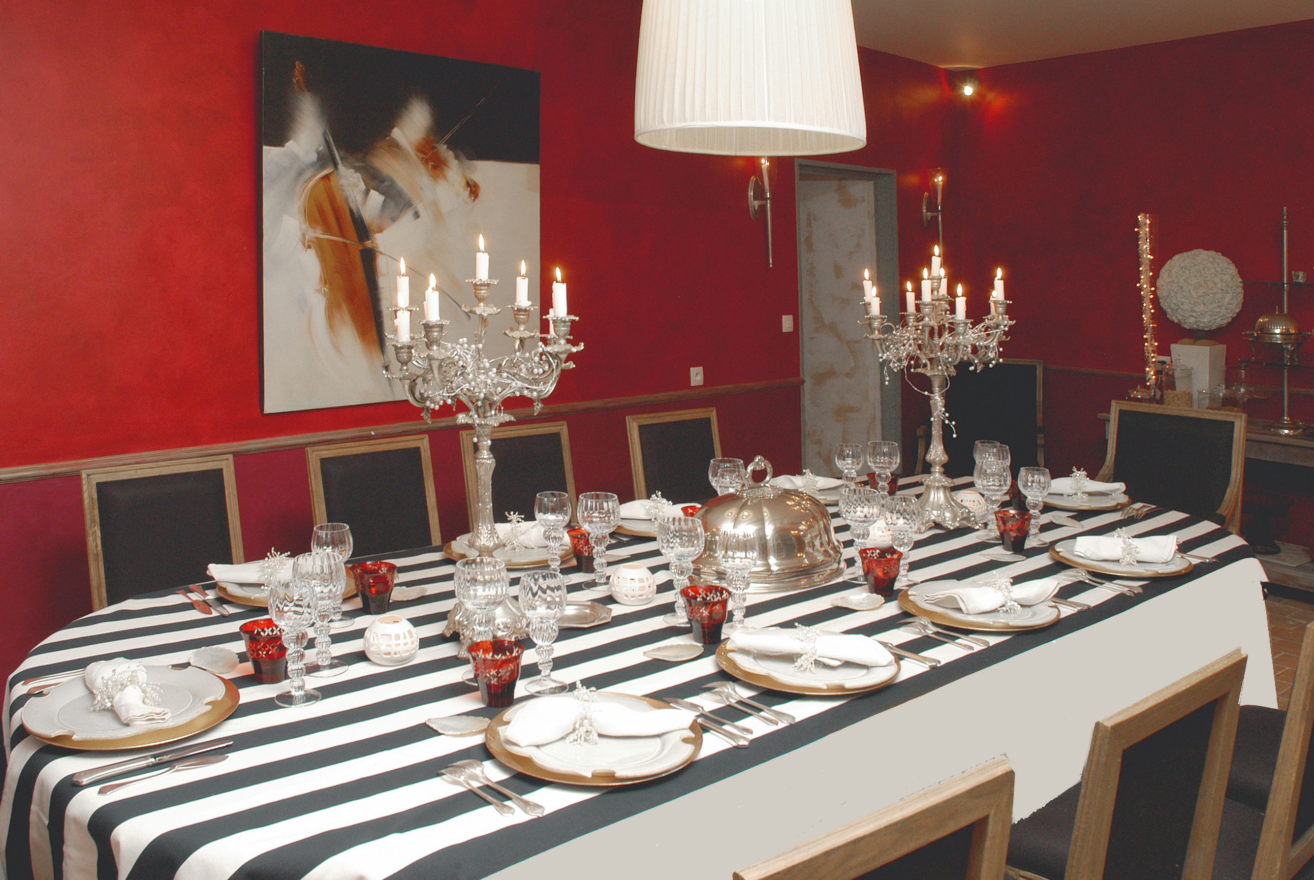 A dining table set for a formal meal with multiple candles, glassware, and silverware.
