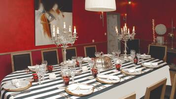 A dining table set for a formal meal with multiple candles, glassware, and silverware.