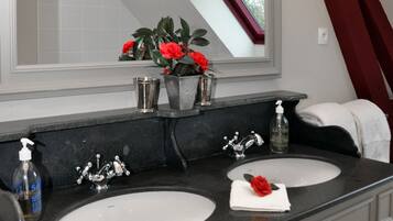 Une salle de bain avec deux lavabos, un grand miroir et un rideau rouge.