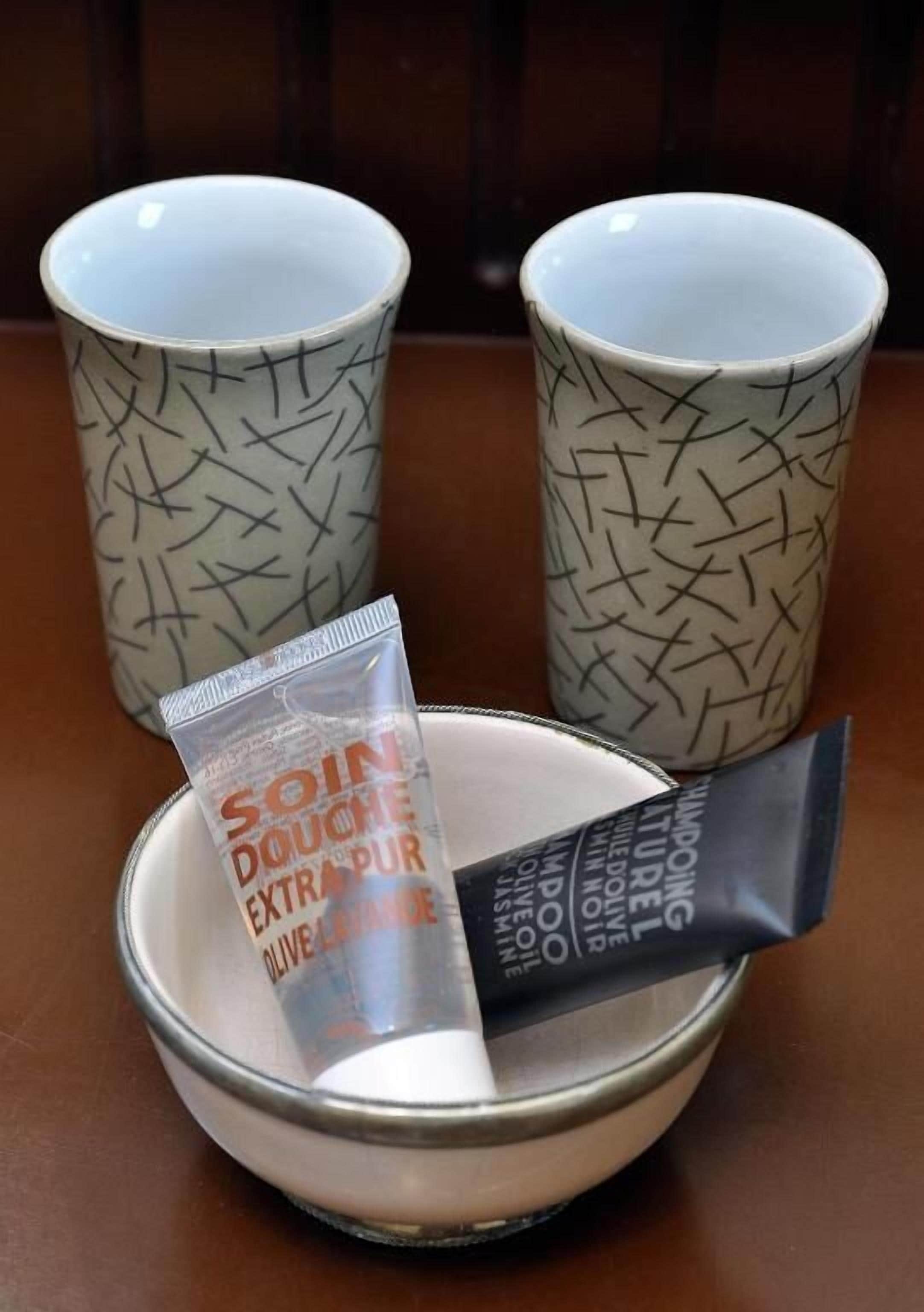 A bowl with two tubes of hair care product and two patterned mugs.
