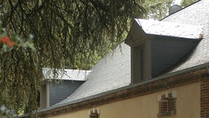 A building with a brick facade, large windows, and a gravel driveway. - La Demeure de l'Ile (Craon)