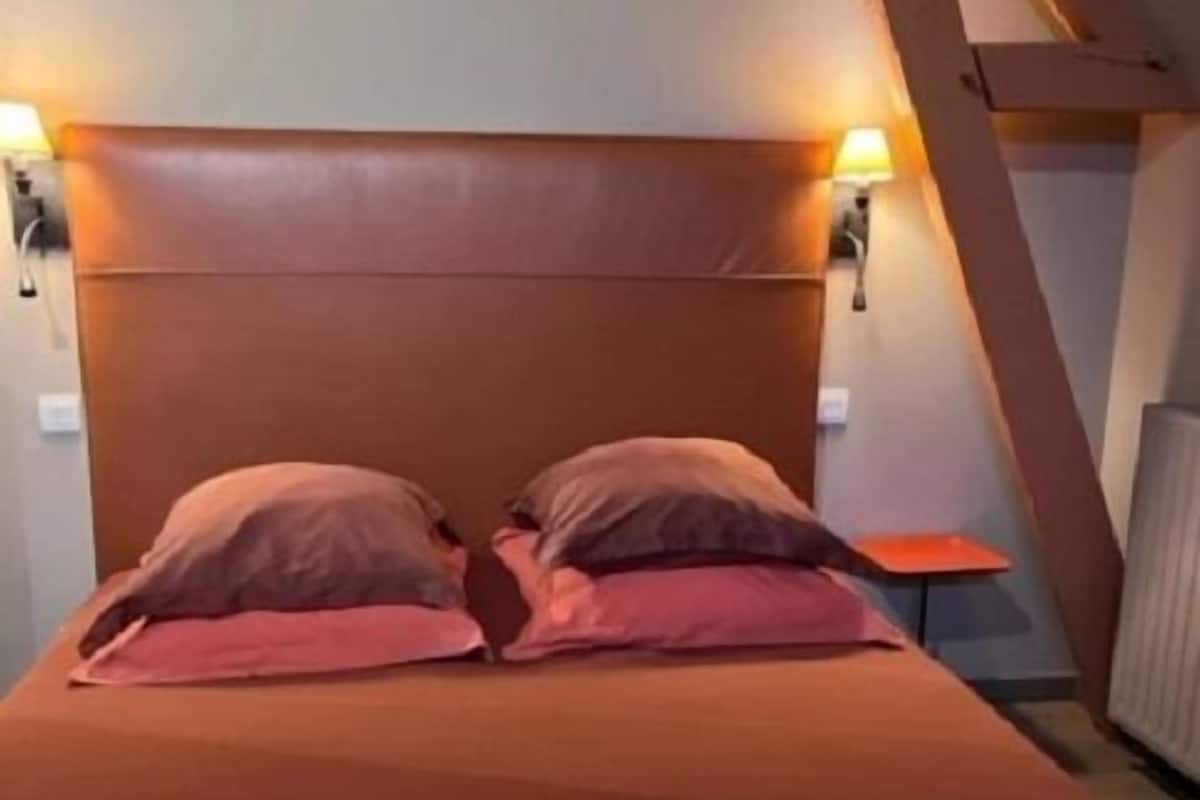 A bedroom with a wooden headboard, two bedside lamps, and a small table beside the bed.