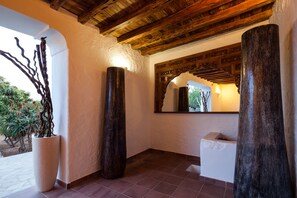 A hallway with a rustic ceiling, a large mirror, and a potted plant.