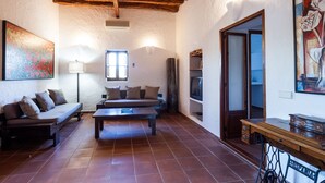 Una sala de estar acogedora con techo de madera, un sofá, una mesa de centro y un televisor.