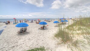 A beach with several blue umbrellas and beach chairs. - 10 Ocean Gate: 2BR, 2.5BA Community Pool, Short Walk to Beach, Free Bikes (Hilton Head Island)