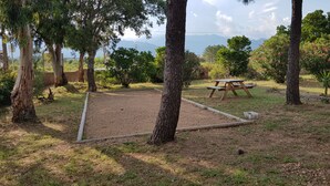 A picnic area with a table and benches, surrounded by trees and a view of distant mountains. - Small house 4/6 persons 700 m from the beach of st cyprien (Porto-Vecchio)
