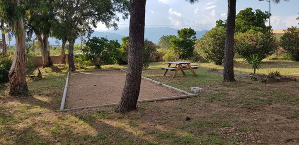 A picnic area with a table and benches, surrounded by trees and a view of distant mountains.