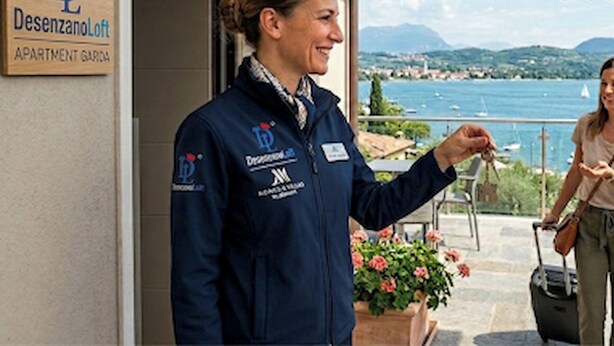 A person standing at a hotel entrance with a sign reading 'Desenzano Loft APARTMENT GARDEN'. - Desenzanoloft Garden and Pool (Desenzano del Garda)