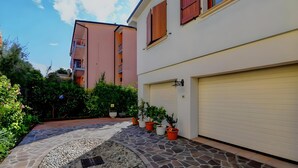 A residential building with a garage, a stone pathway, and potted plants. - Desenzanoloft Garden and Pool (Desenzano del Garda)