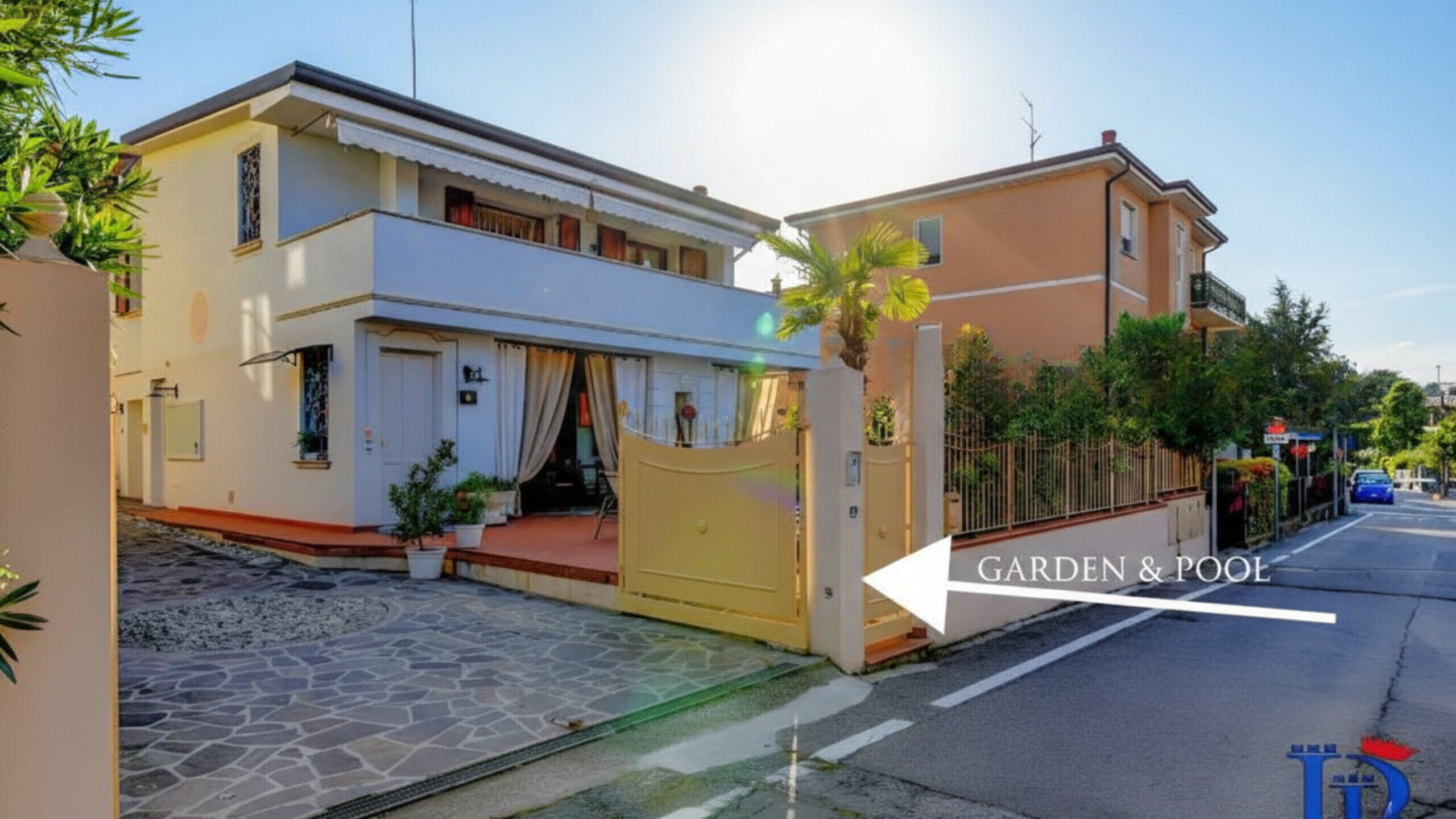 A residential property with a stone-paved entrance, a gated garden area, and a pool.