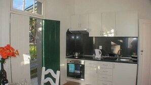 A compact kitchen with white cabinets, a black countertop, and a built-in oven. -  Typical Farm Apartment, sunny views. (Arco Da Calheta)