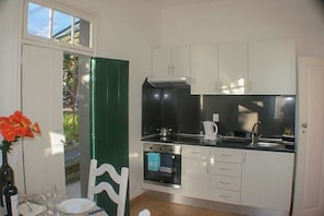 A compact kitchen with white cabinets, a black countertop, and a built-in oven.