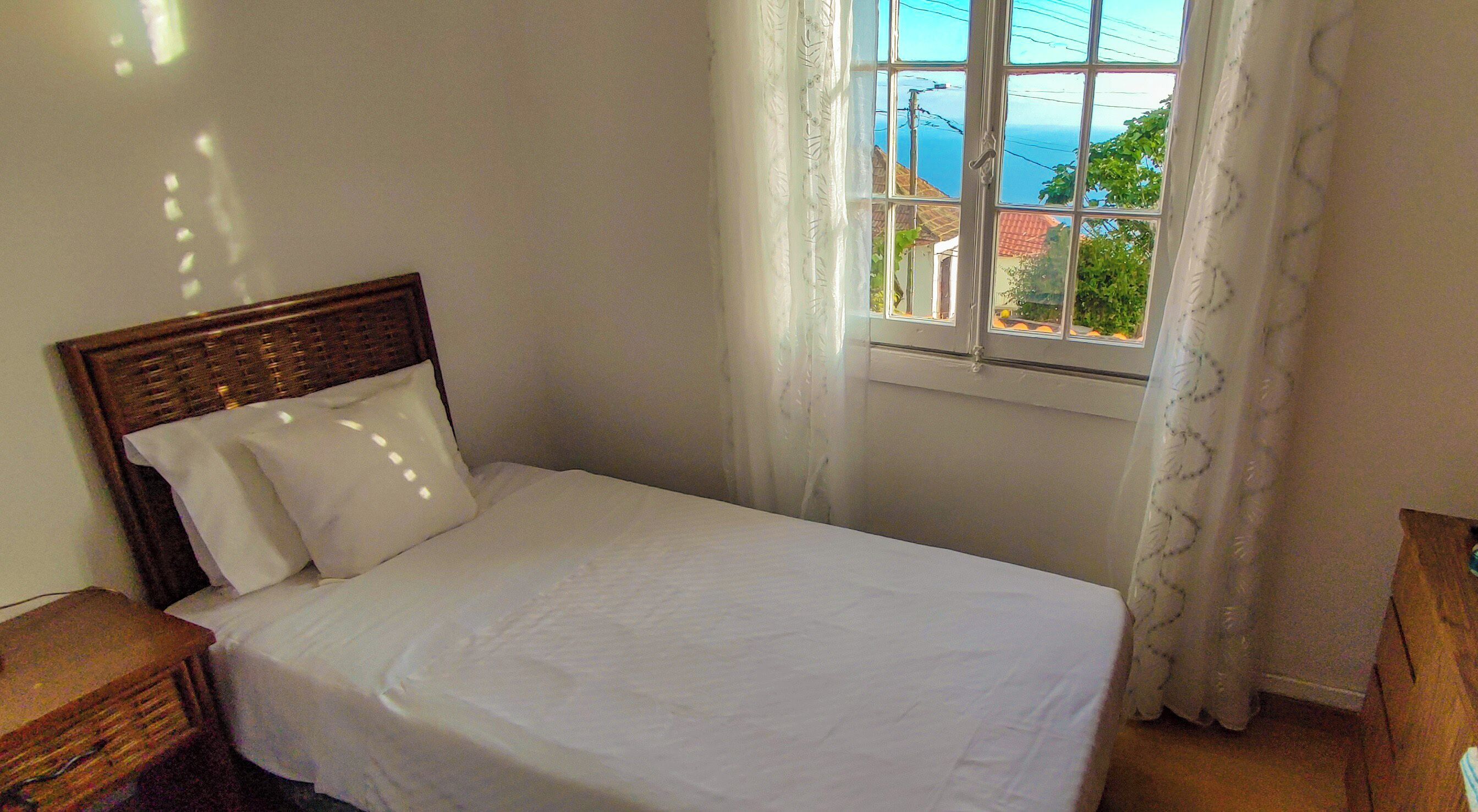 Una cama individual con ropa blanca en una habitación con ventana.