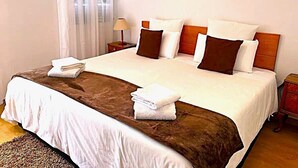 A double bed with white and brown bedding, a wooden headboard, and two bedside tables with lamps. -  Typical Farm Apartment, sunny views. (Arco Da Calheta)